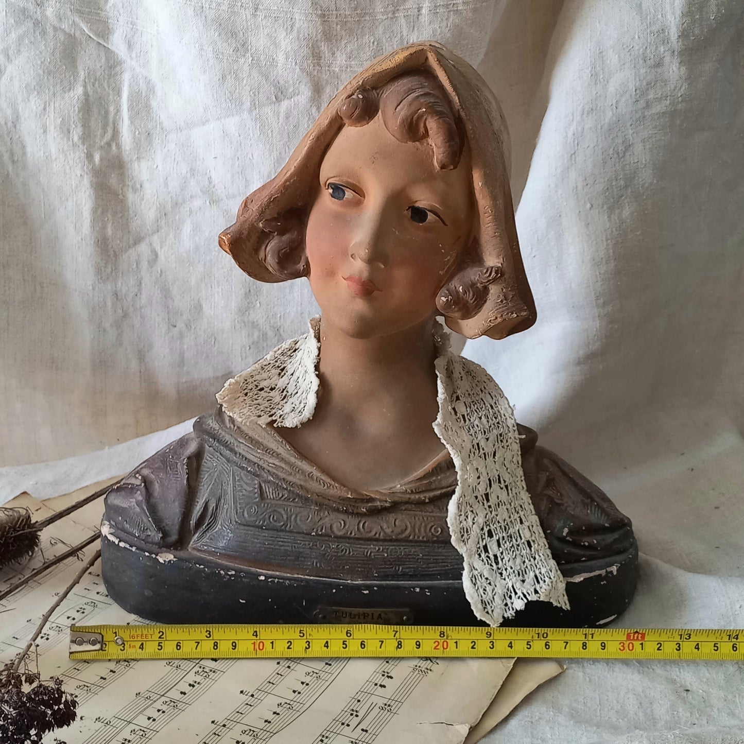 Antique bust of a woman wearing a bonnet on a white fabric background