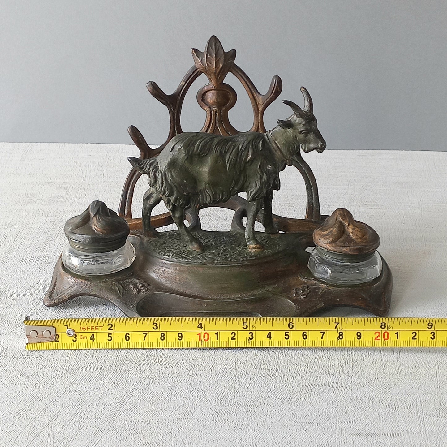 A stunning French art nouveau double inkwell with a goat figurine.
This wonderful antique inkwell has been sculpted in metal and signed by the artist (see photos). Behind the beautiful goat figurine are two pen rests and either side of the goat are two small glass ink pots with decorative metal lids.
The metal is finished in a lovely shade of green that has worn over time with traces of gold colour beneath - it has a wonderful patina of time all over it.