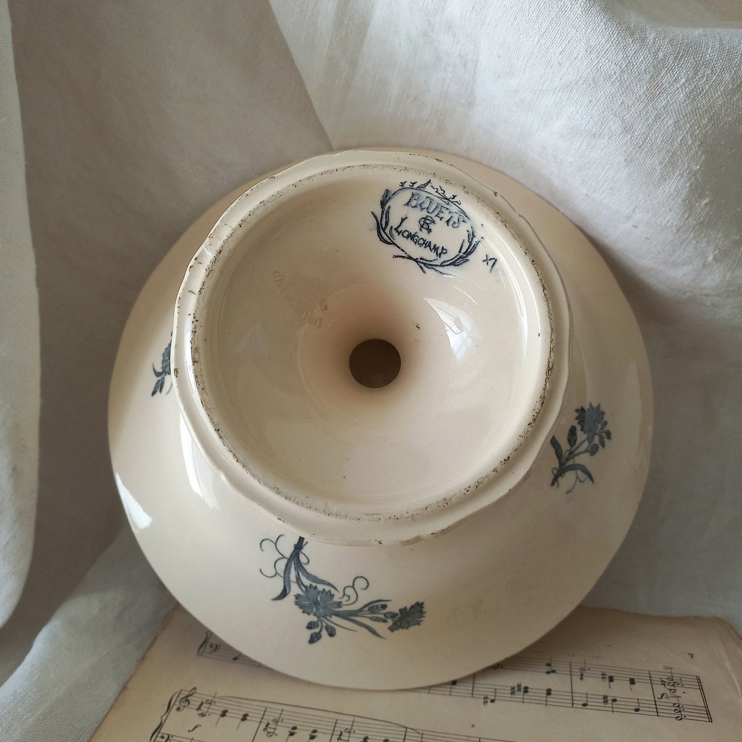 A beautiful antique compote or footed bowl by French manufacturer Longchamp. The main colour is a warm cream/white with blue floral transferware pattern.