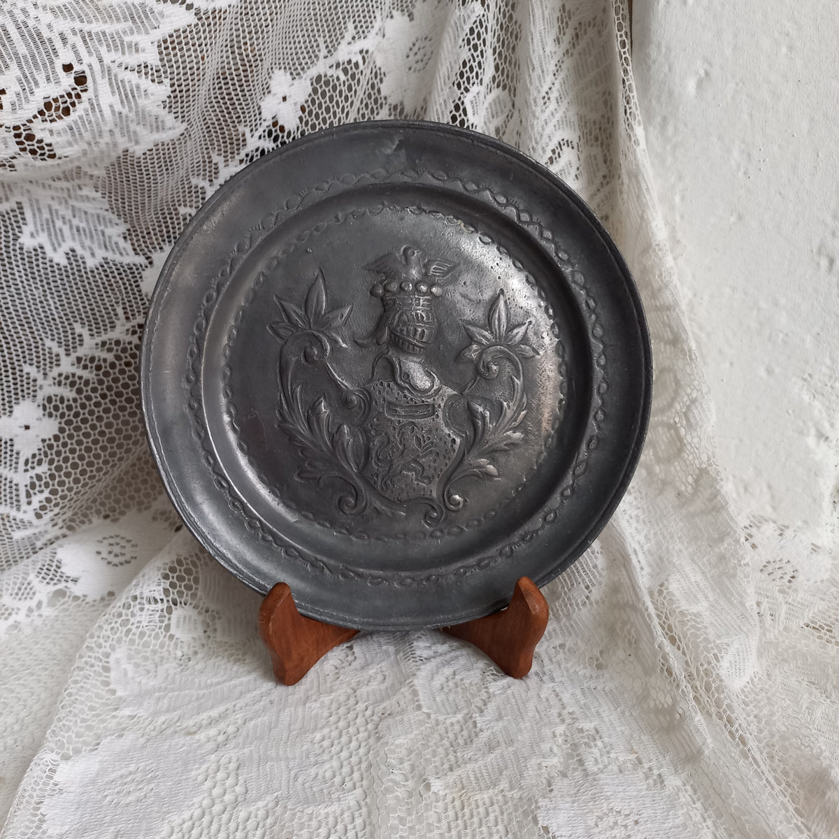 A small French vintage or antique embossed pewter plate with coat of arms depicting armor.