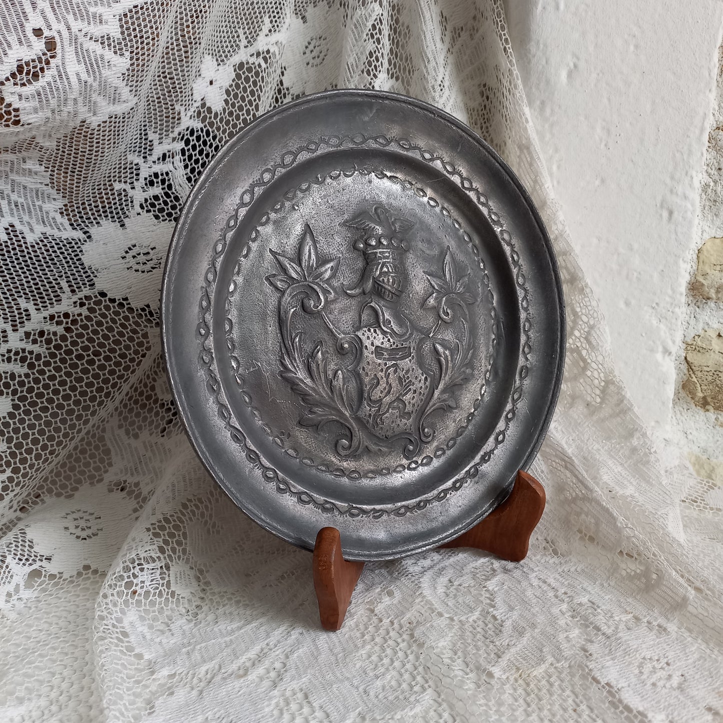 A small French vintage or antique embossed pewter plate with coat of arms depicting armor.