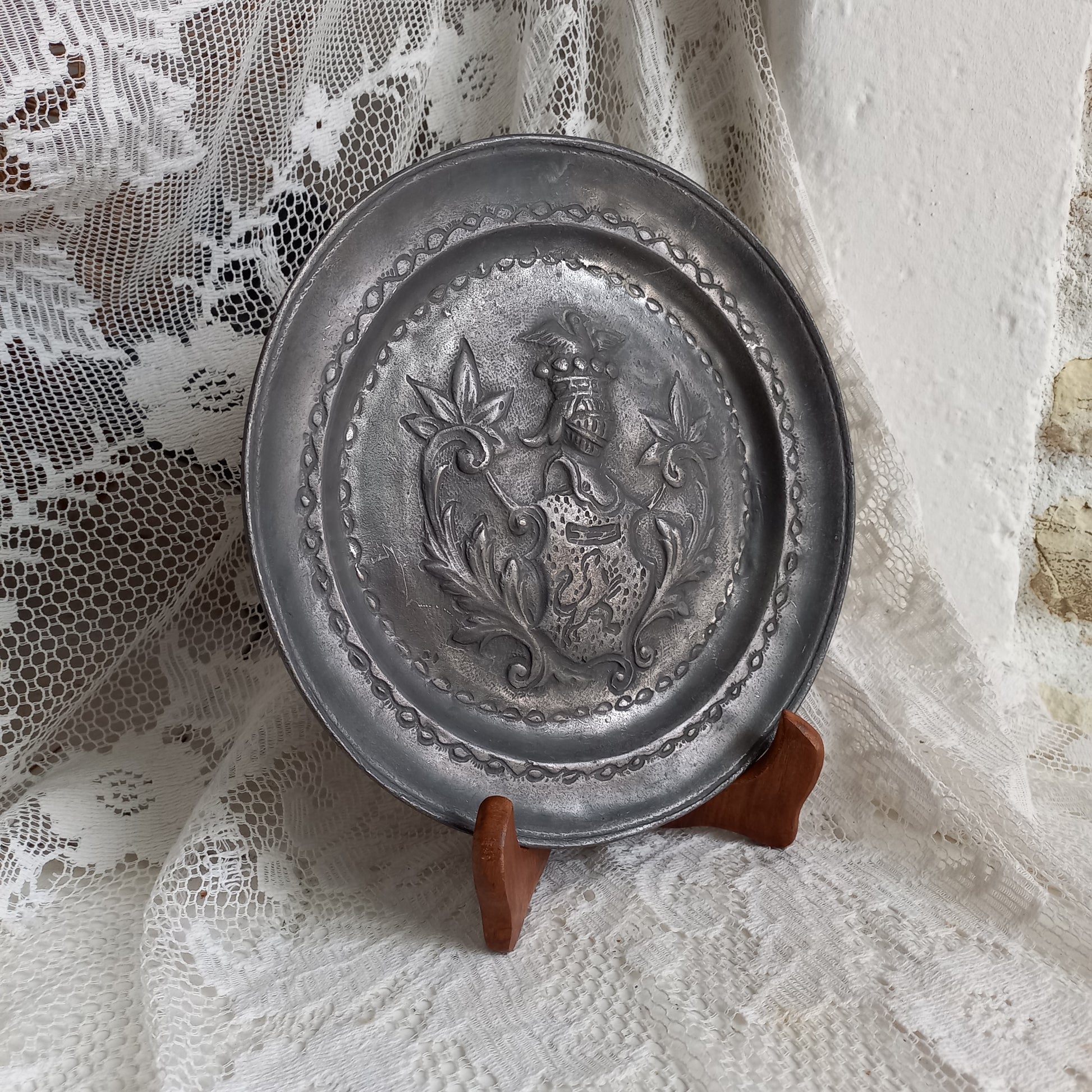 A small French vintage or antique embossed pewter plate with coat of arms depicting armor.