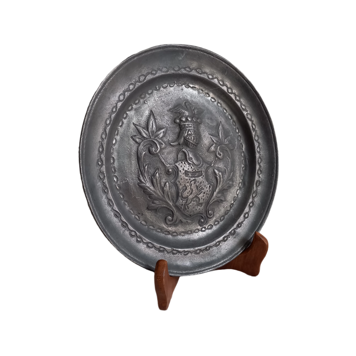 A small French vintage or antique embossed pewter plate with coat of arms depicting armor.