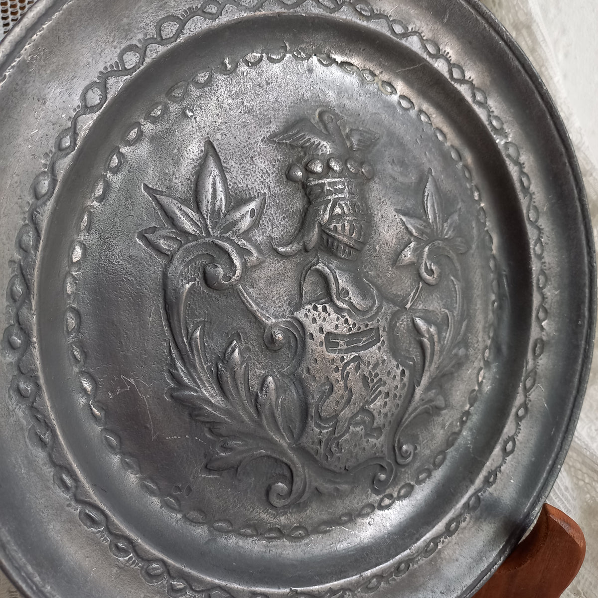 A small French vintage or antique embossed pewter plate with coat of arms depicting armor.