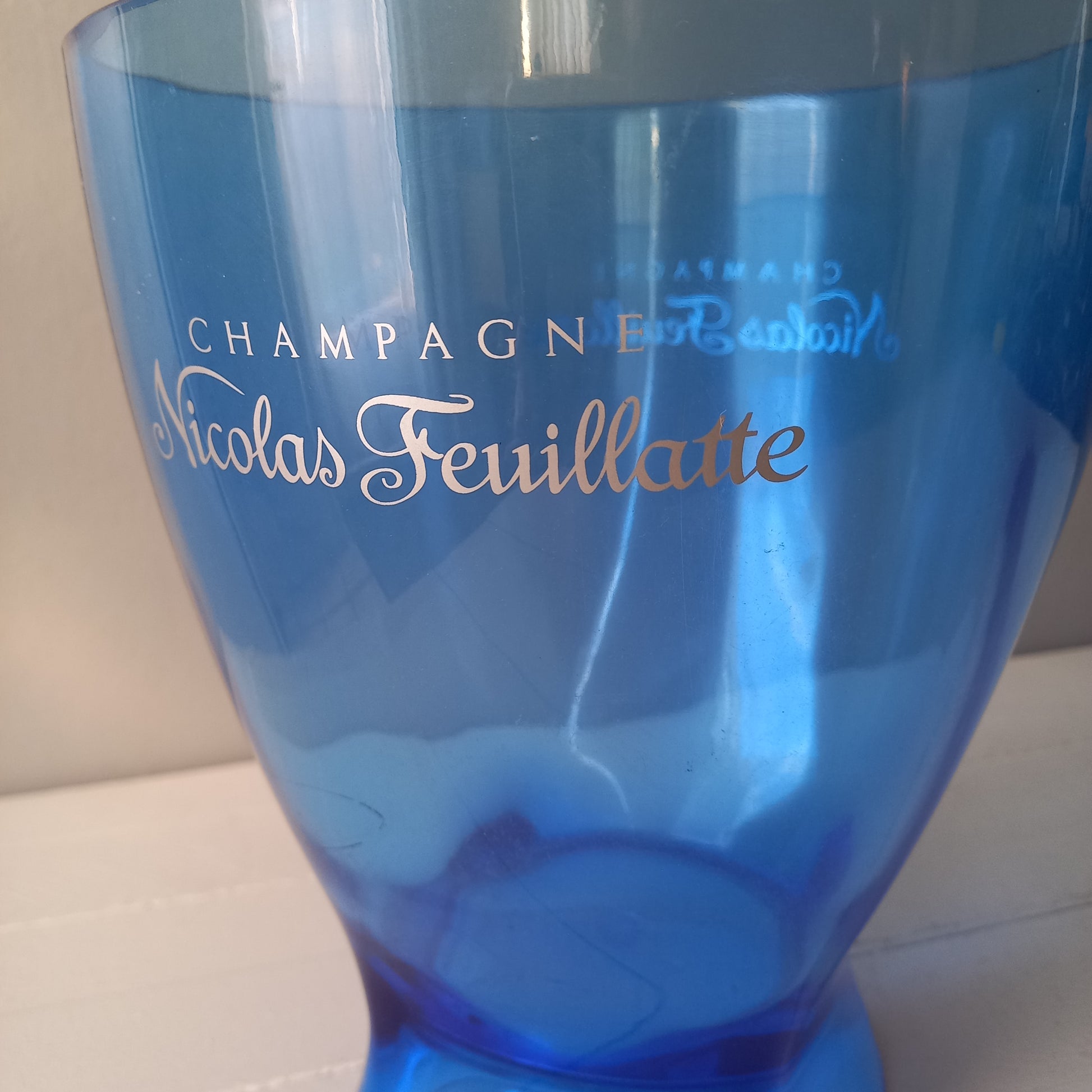 Vintage Nicolas Feuillatte transparent blue champagne bucket made from resin or hardened plastic. Being a vintage item there are of course some scuffs and scratches in the plastic.