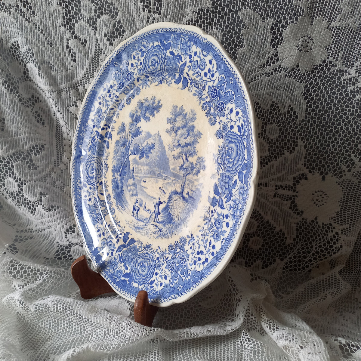 Blue and white decorative plate held over a lace tablecloth