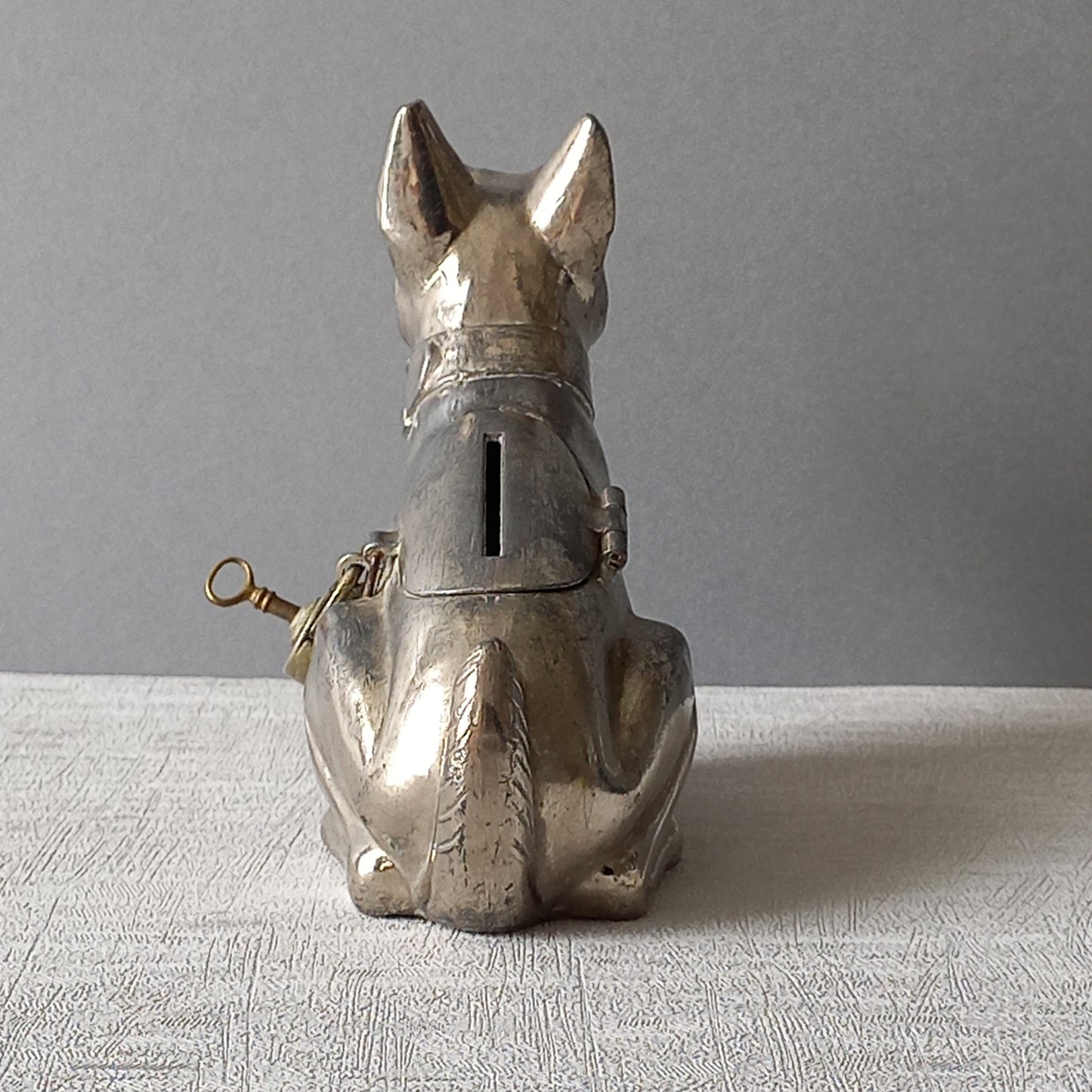 A fabulous French art deco metal terrier dog money box/coin storage box complete with a little padlock and key which still work. 

This unique piece of history was purchased in south west France and we can only imagine who once owned it and what they might have saved their coins to buy.