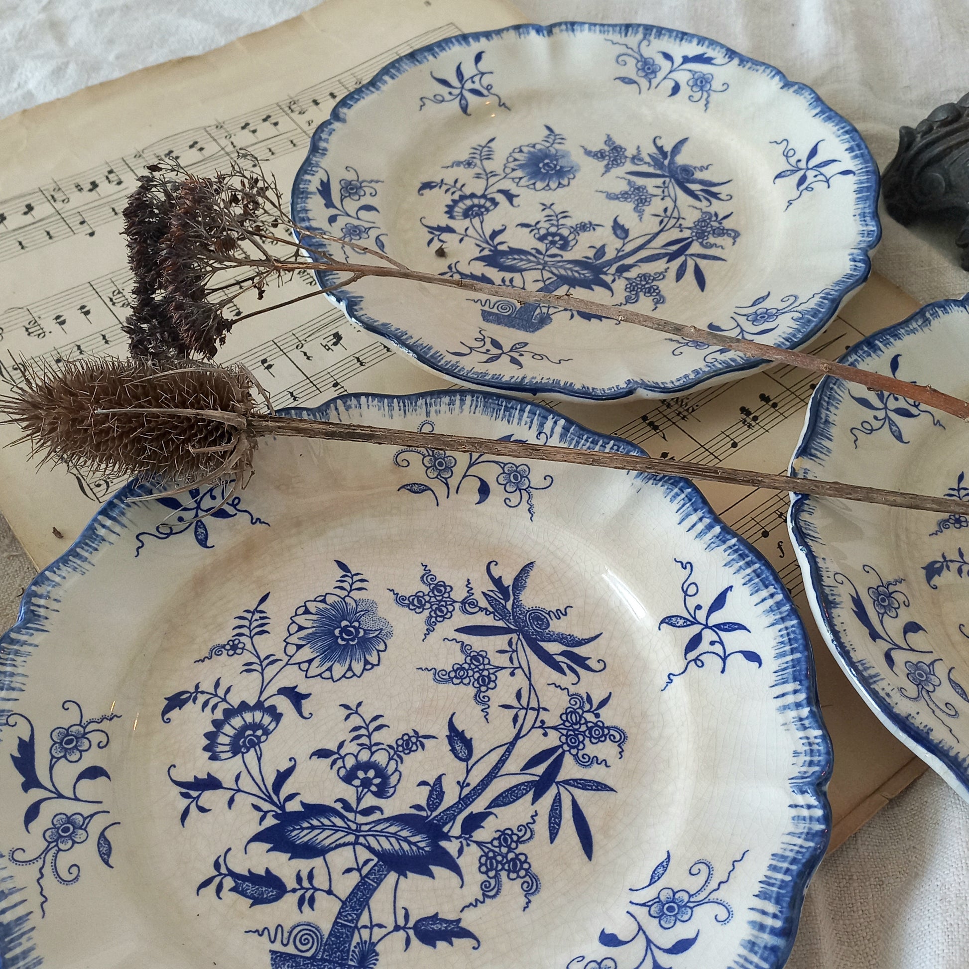 Set of blue and white floral-patterned plates on a surface with sheet music.