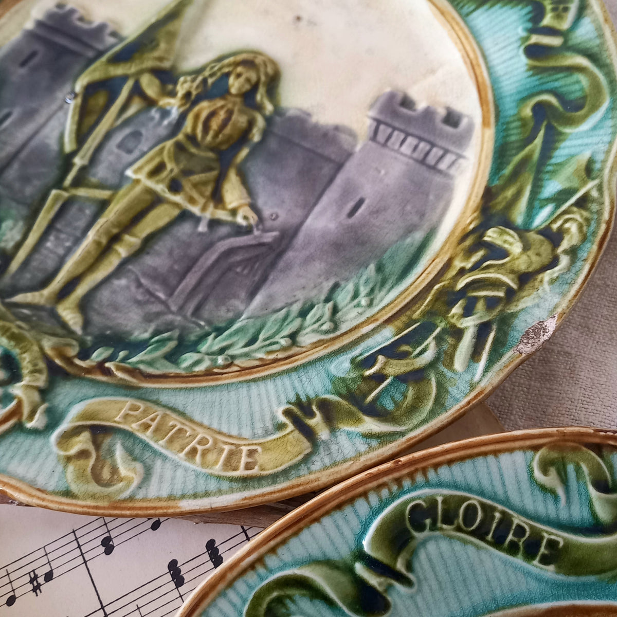 Decorative ceramic plate with a castle and figure design, featuring the word 'PATRIE'.