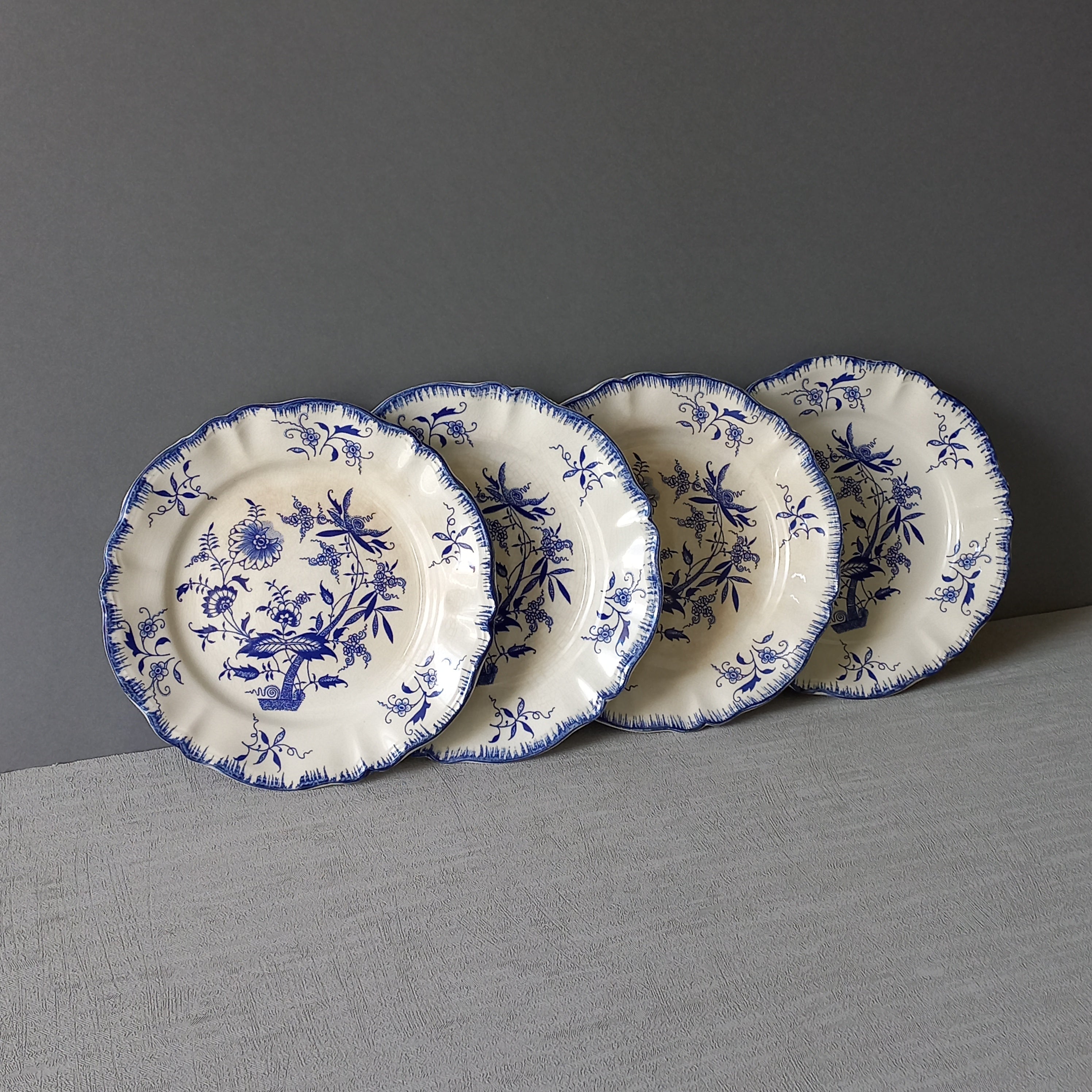 A stunning set of 4 small antique white ironstone plates with blue floral patterns from France.