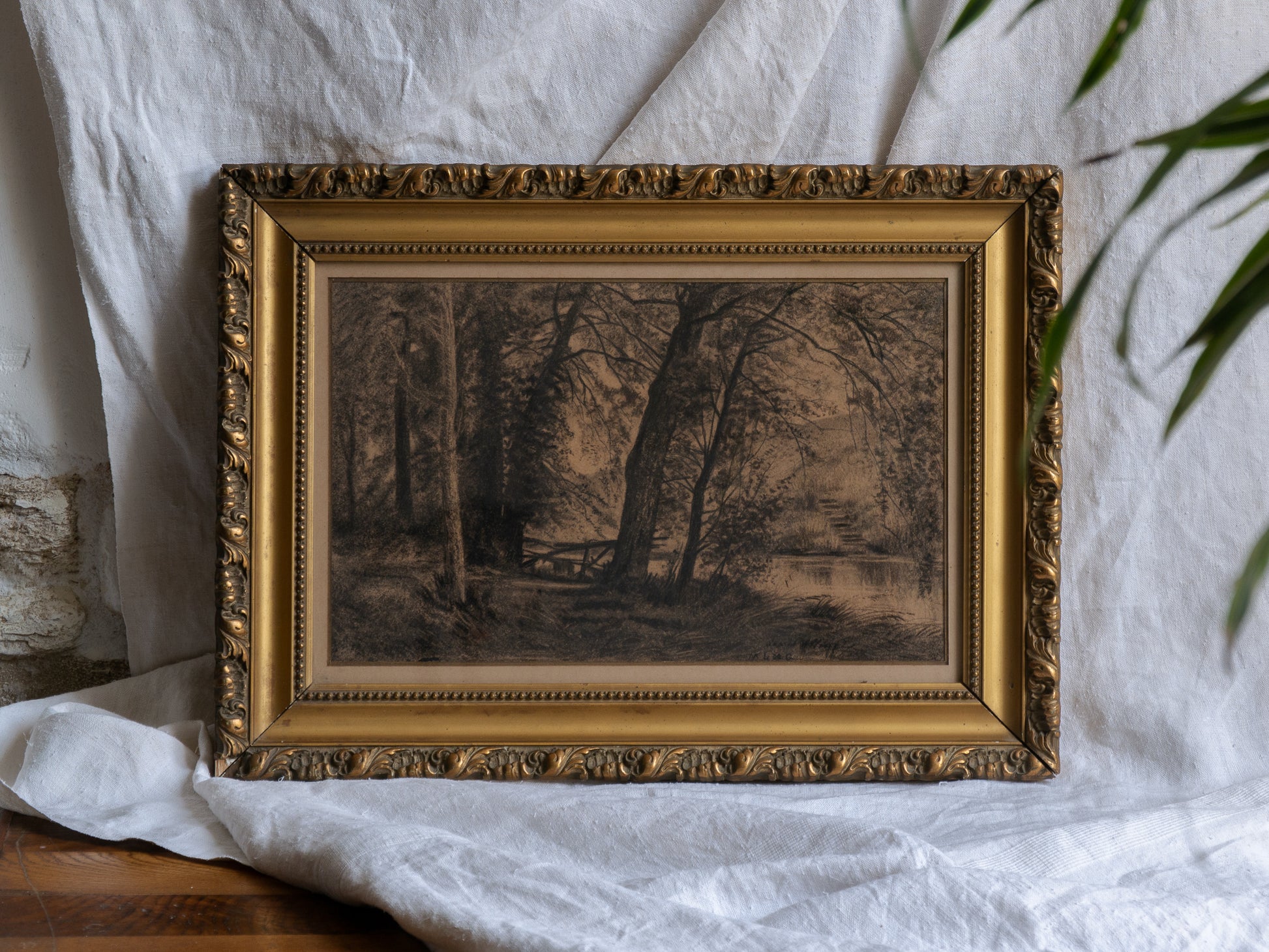 Framed artwork of a landscape with trees on a white fabric background