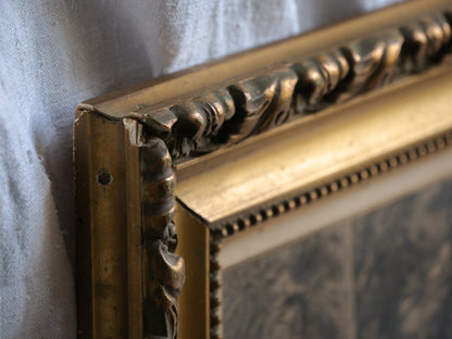 Close-up of an ornate gold picture frame corner on a textured surface.