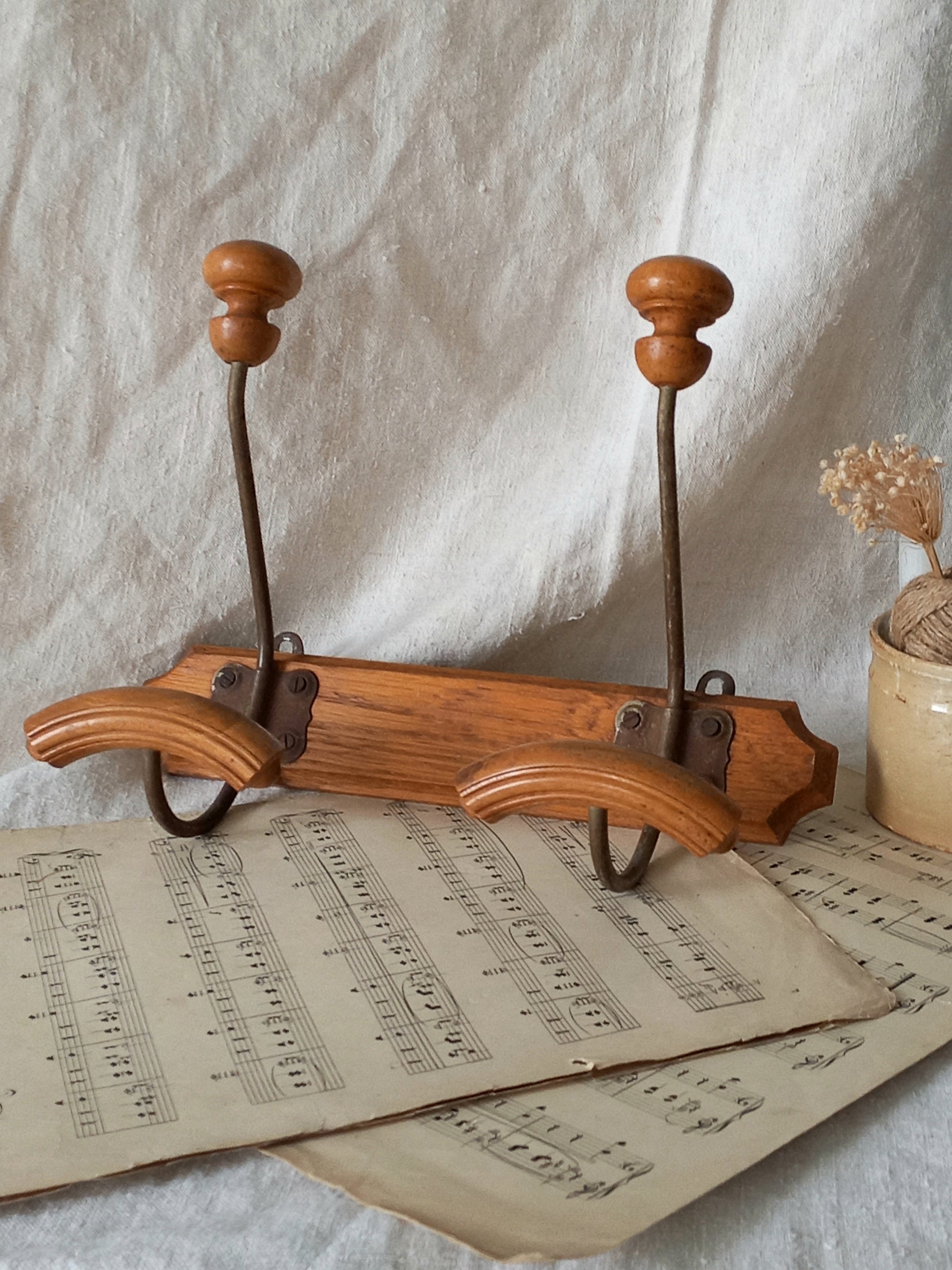 Wooden coat rack with two hooks on an old sheet of music, against a textured white background.