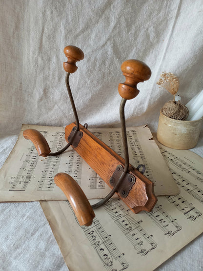 French vintage coat and hat rack with 2 metal hooks, each hook having wooden pegs for a hat and a coat.
