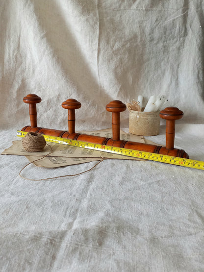 French Antique Faux Bamboo Coat Rack with Four Pegs in rustic setting with tape measure for reference