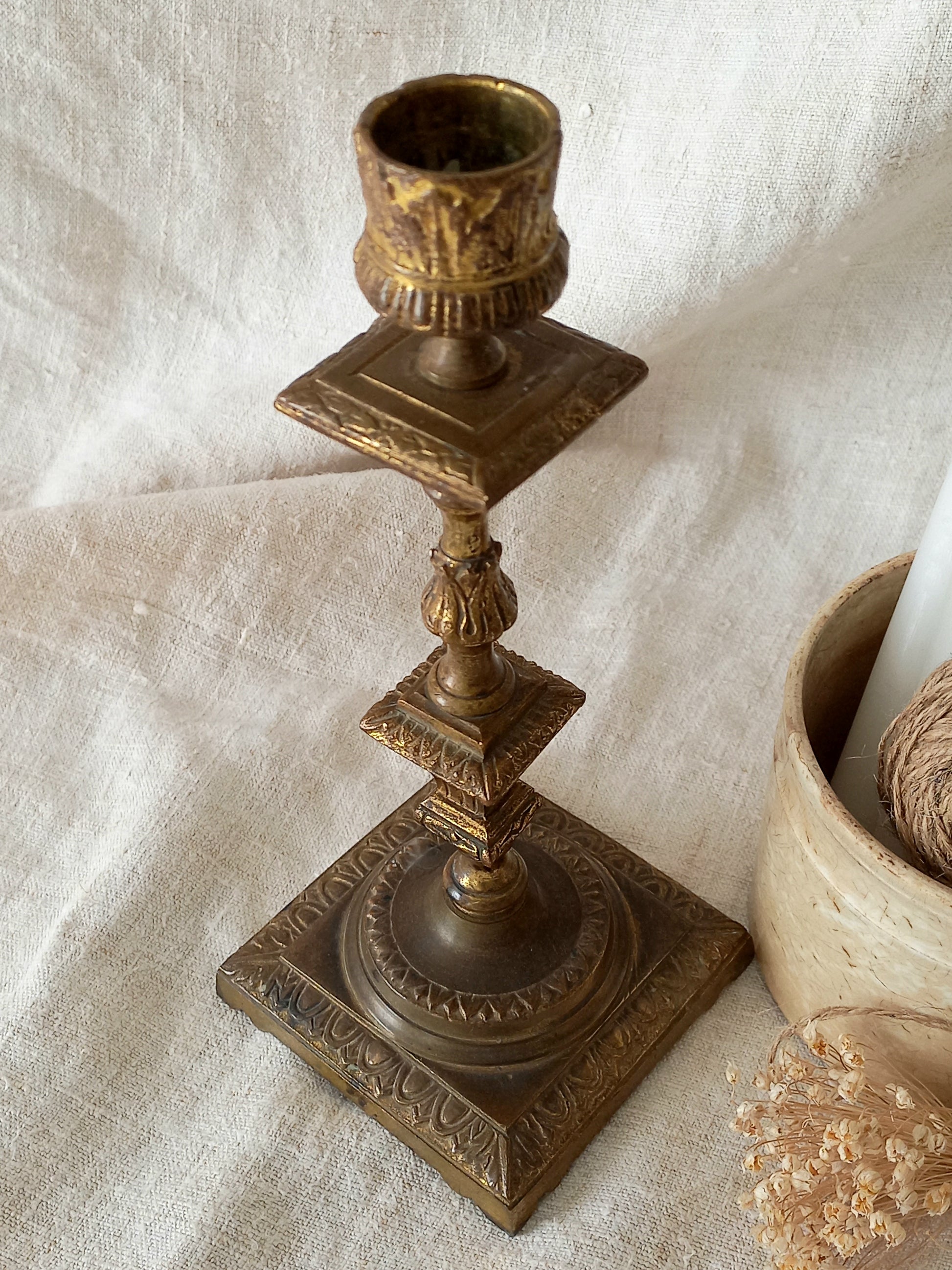 Decorative bronze candlestick on a textured white surface