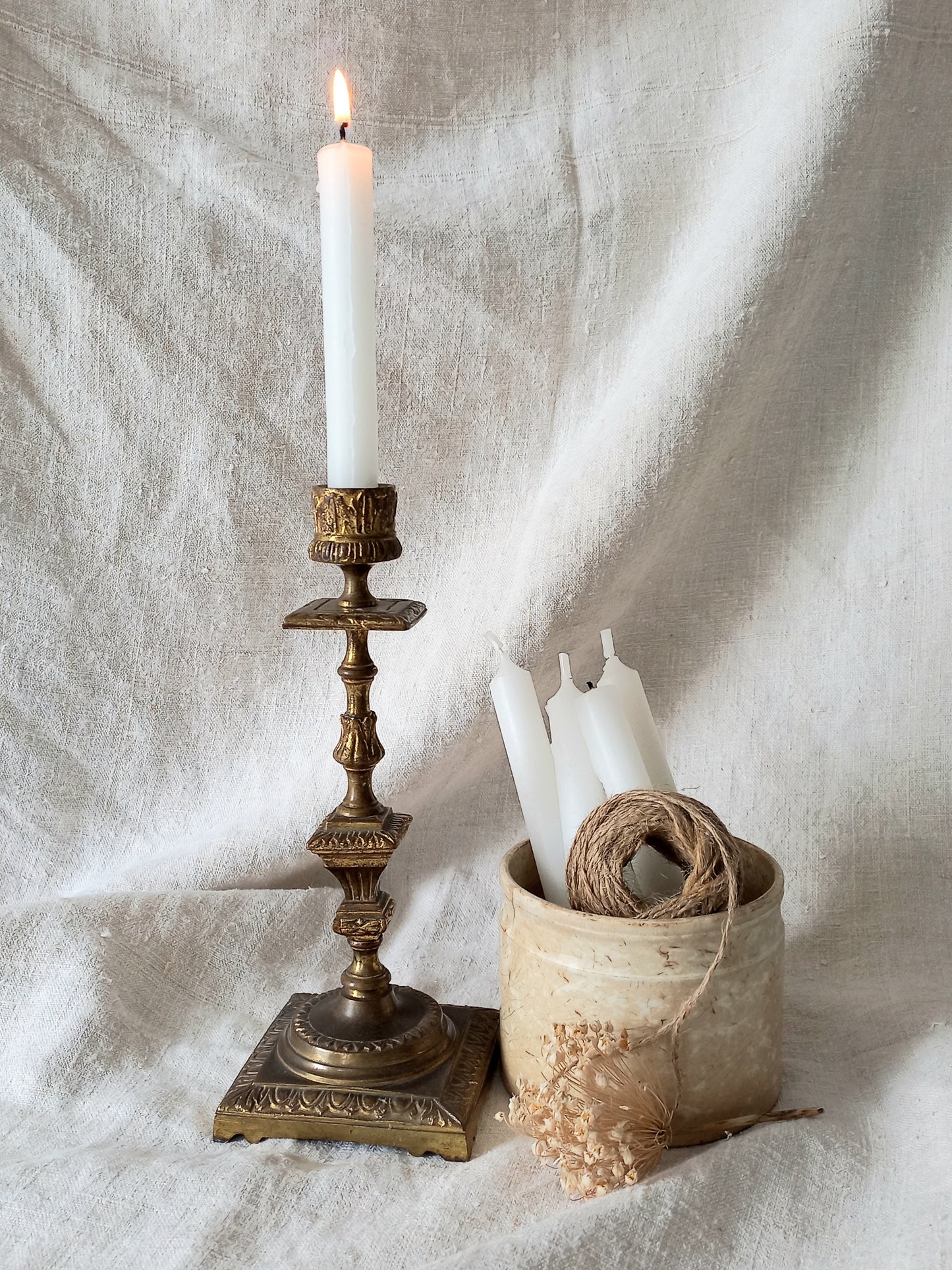 Decorative candlestick with a lit candle on a textured fabric background