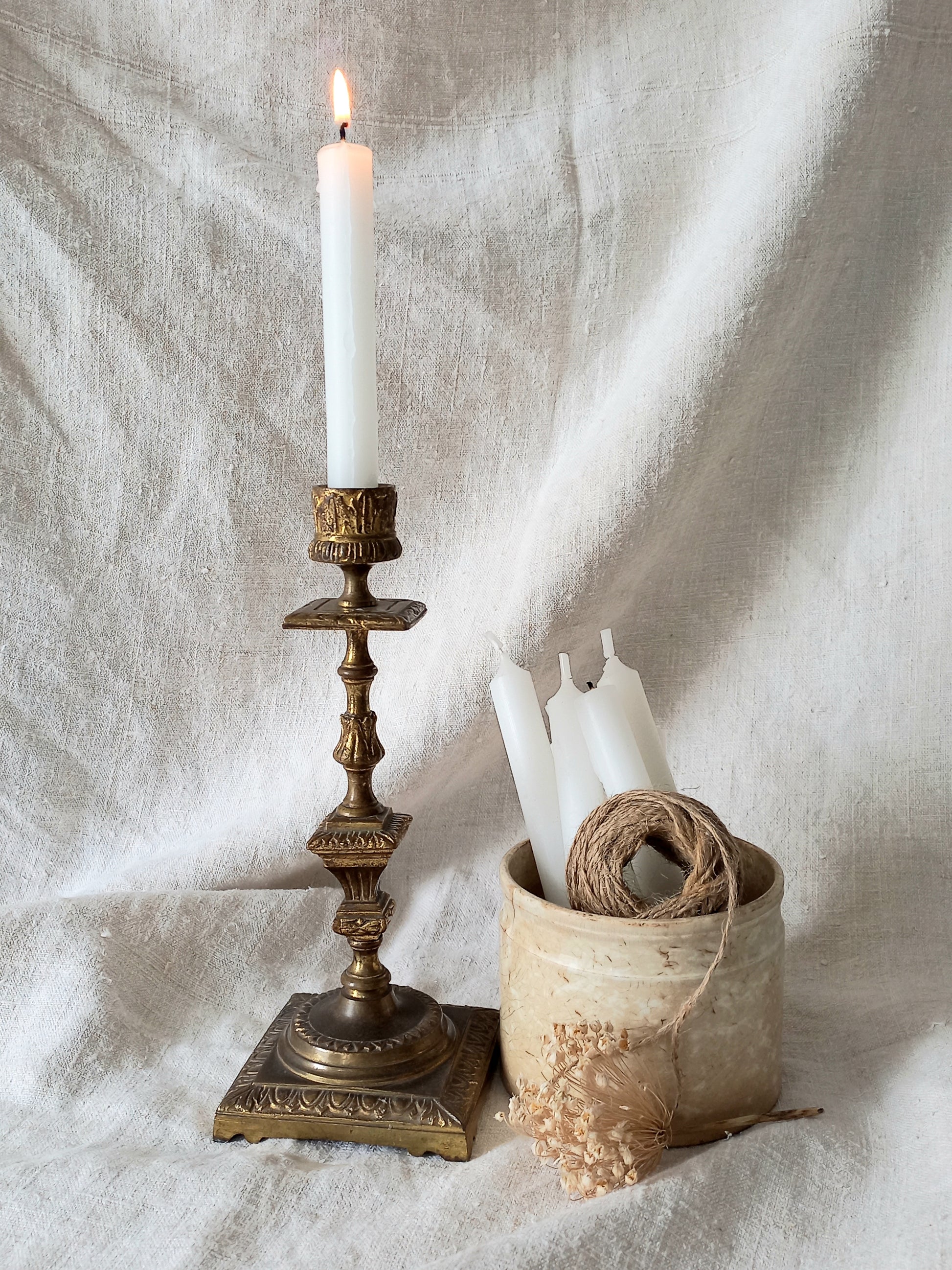 Decorative candlestick with a lit candle on a textured fabric background