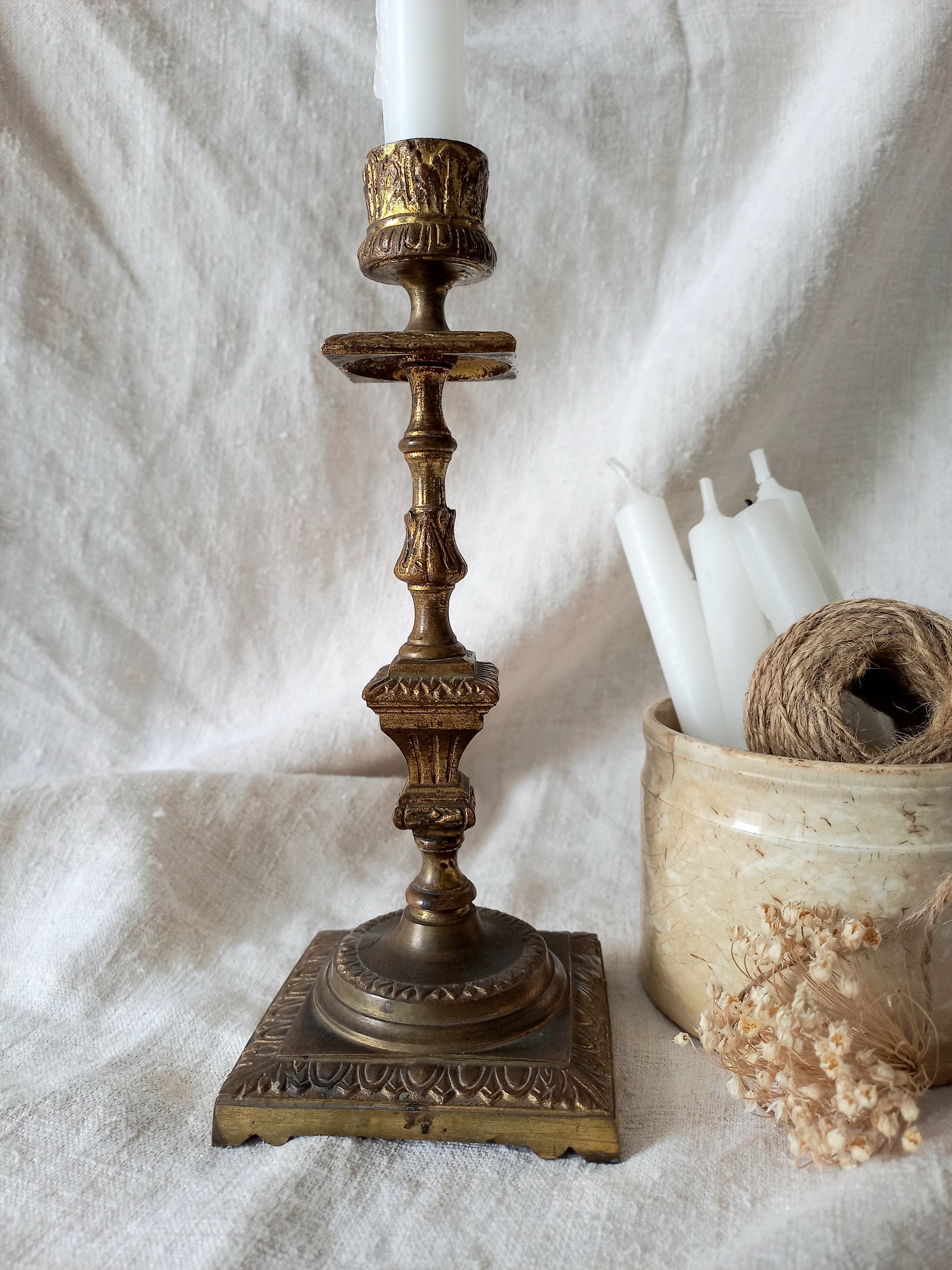 Decorative brass candlestick with white candles on a textured white surface