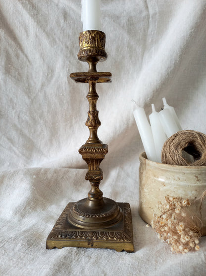 Decorative brass candlestick with white candles on a textured white surface