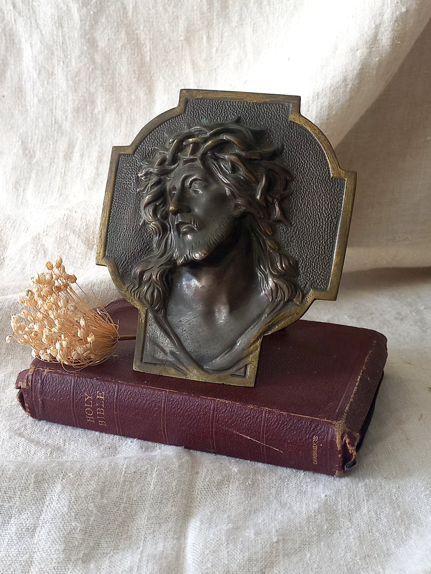 Bronze table-top Crucifix with a Jesus Christ bust design on a textured surface