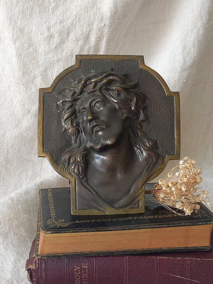 Bronze table-top Crucifix with a Jesus Christ bust design on a textured surface