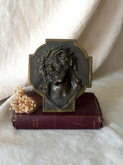 Bronze table-top Crucifix with a Jesus Christ bust design on a textured surface