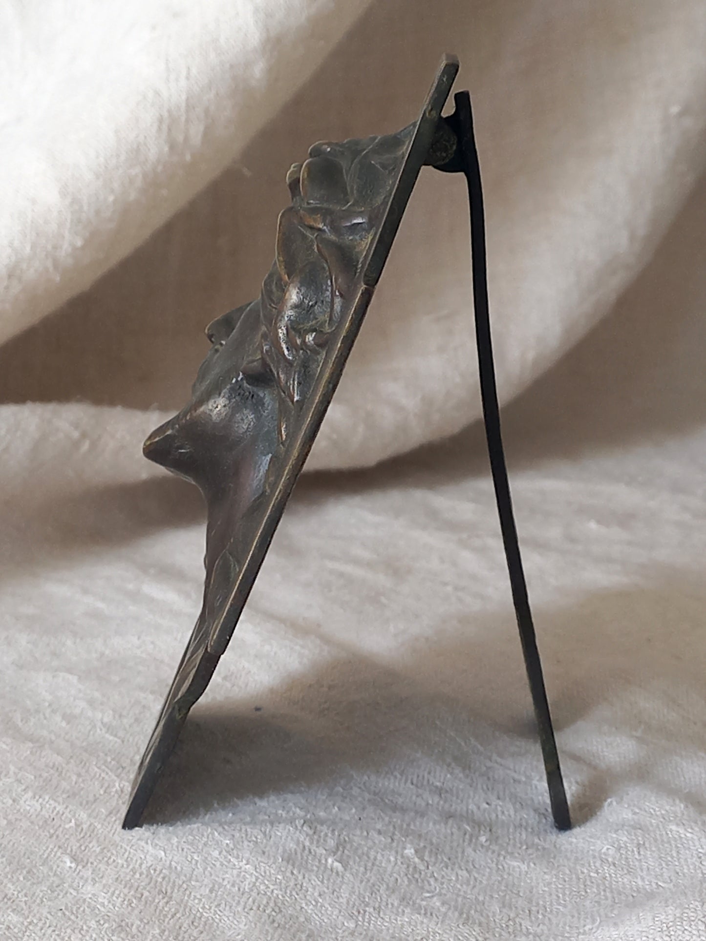 Side view of Bronze table-top Crucifix with a Jesus Christ bust design on a textured surface