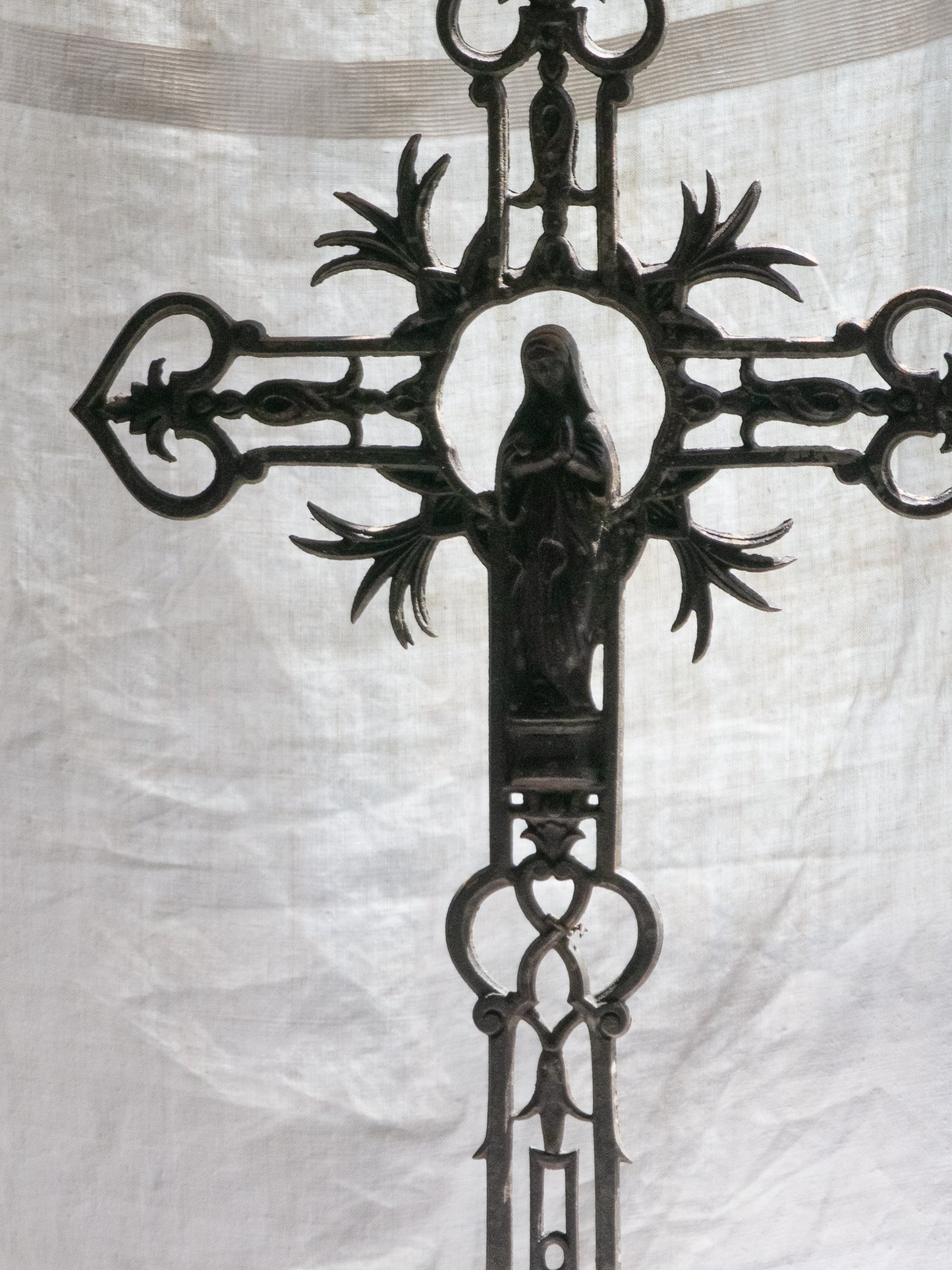 A large French antique crucifix in cast or wrought iron, featuring a figure of the Madonna at its center. Likely once part of a larger architectural structure, this rare piece carries visible signs of age and long exposure to the elements.