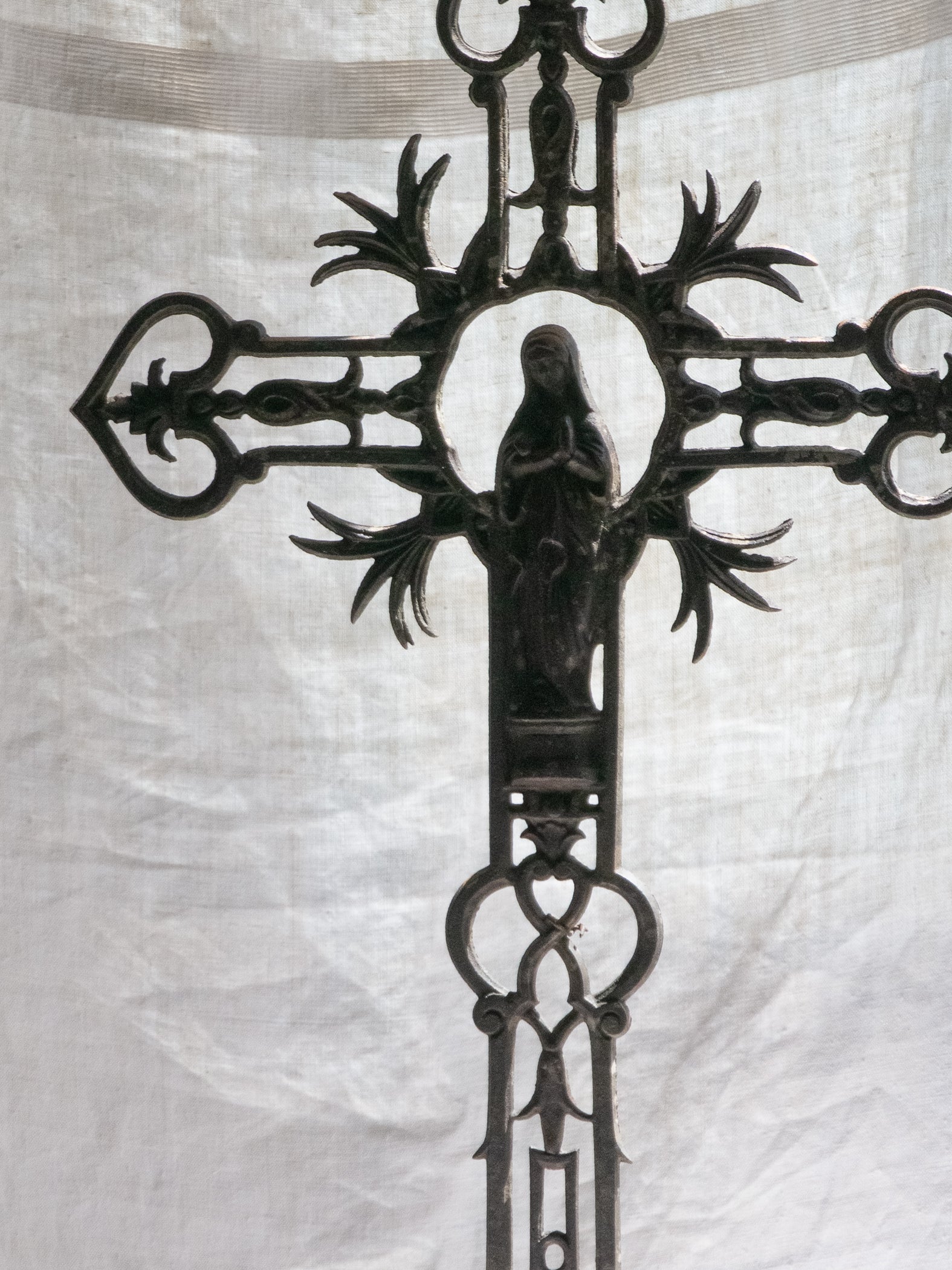 A large French antique crucifix in cast or wrought iron, featuring a figure of the Madonna at its center. Likely once part of a larger architectural structure, this rare piece carries visible signs of age and long exposure to the elements.
