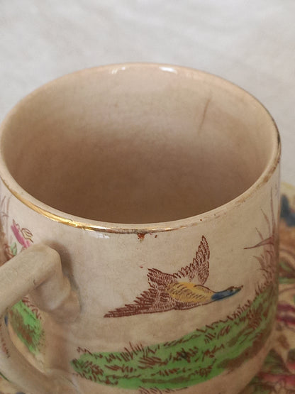 A little antique cup with oriental influenced design depicting ducks, butterflies, flowers and bamboo shoots.