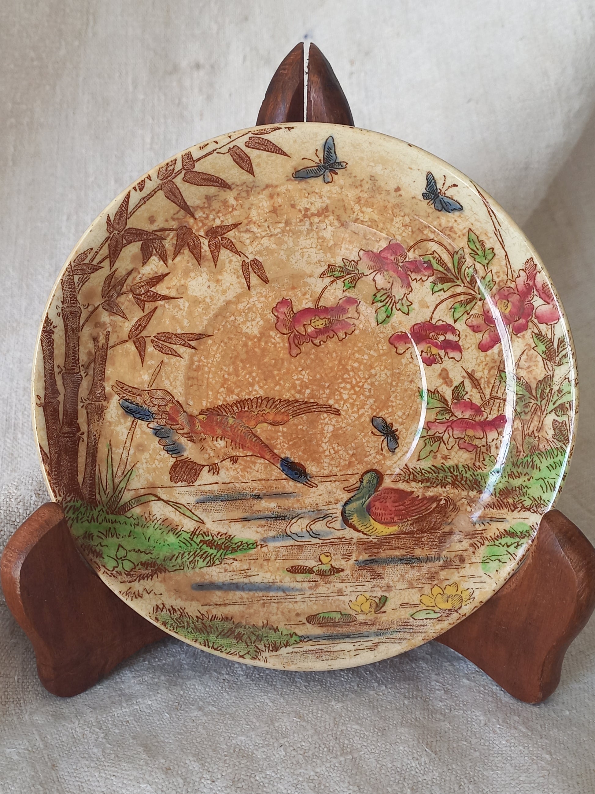 Decorative plate with floral and bird design on a wooden stand