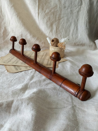 Wooden coat rack with five hooks on a textured white fabric background