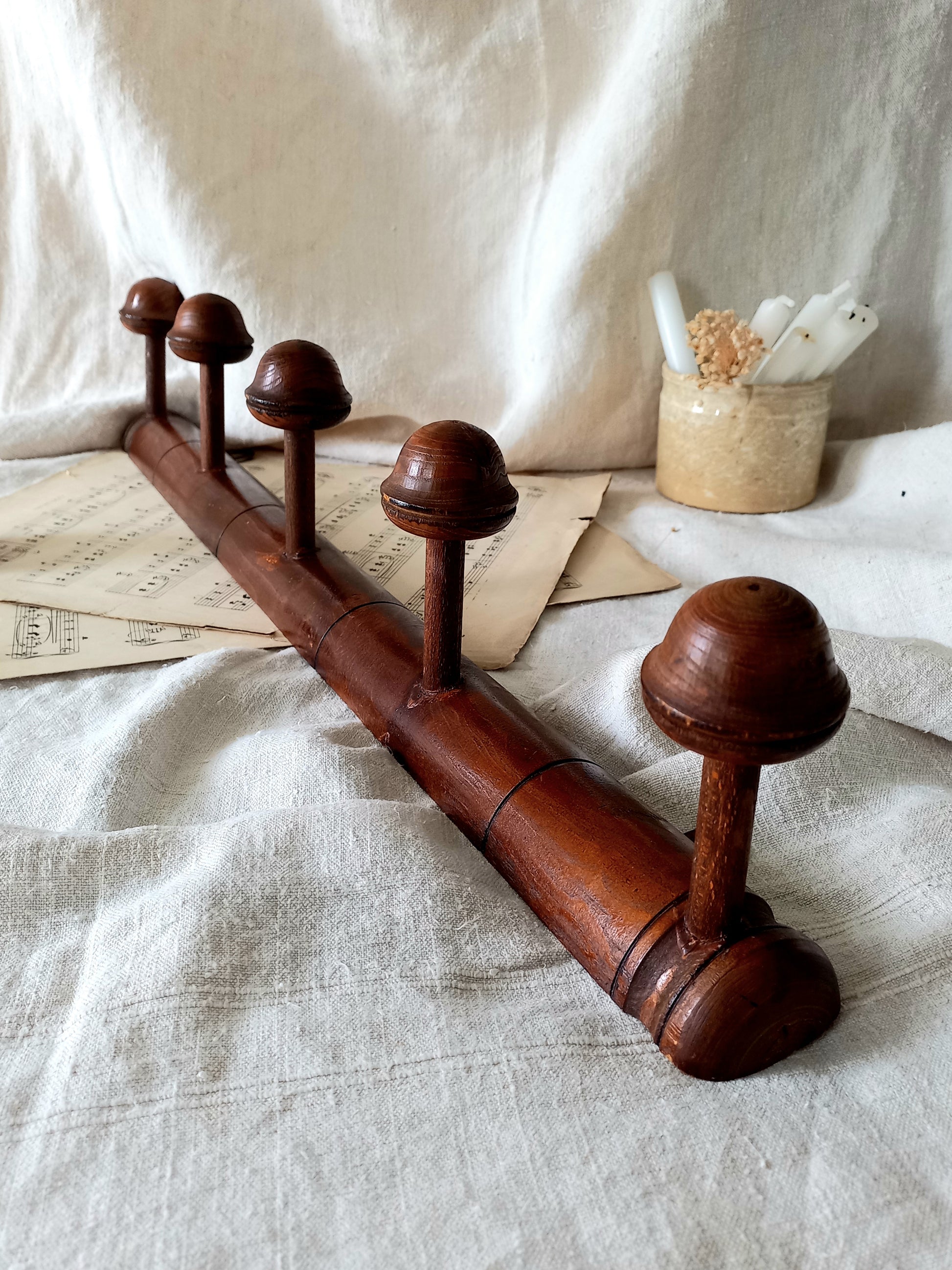 Wooden coat rack with five hooks on a textured fabric background