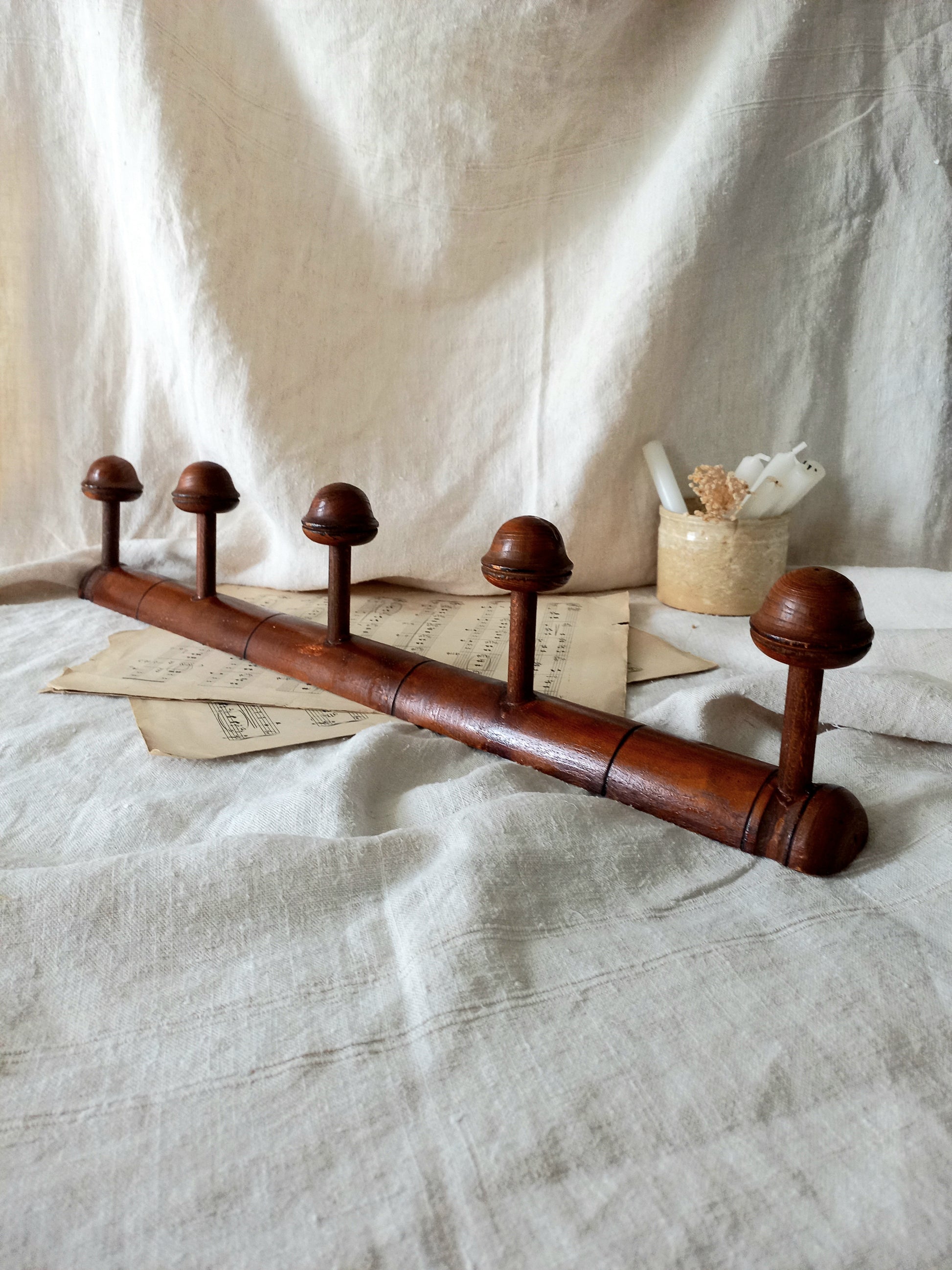 Wooden coat rack with five hooks on a textured fabric background