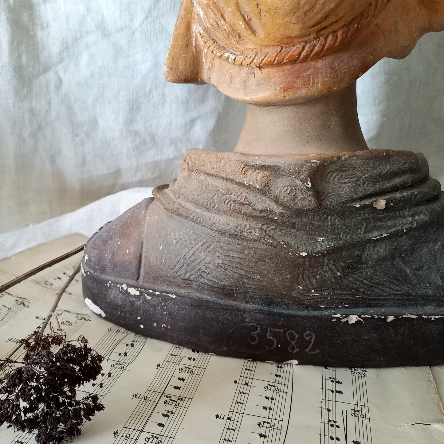 Antique bust of a woman wearing a bonnet on a white fabric background