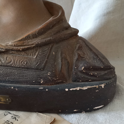 Antique bust of a woman wearing a bonnet on a white fabric background