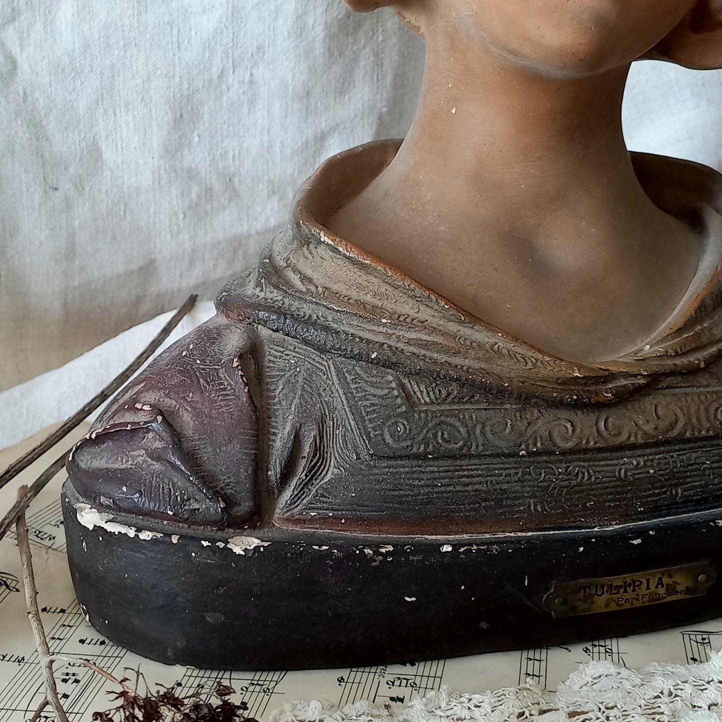 Antique bust of a woman wearing a bonnet on a white fabric background