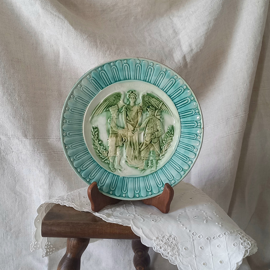 A French antique decorative majolica plate with stunning blue/green colours and an interesting historical background.

This lovely old plate was manufactured as a commemorative piece to celebrate the Franco-Russian Alliance made by the French Republic and the Russian Empire between 1891-1894 (military co-operation agreements) – and that lasted until 1917. The plate depicts a Russian and French soldier shaking hands with a winged female angel in between them.