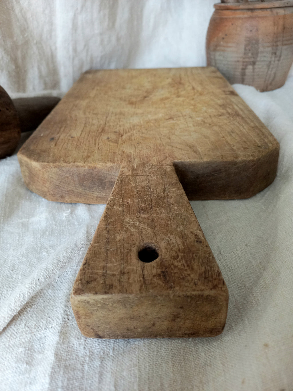 Antique French chunky hand-carved wooden cutting board in a rustic setting.