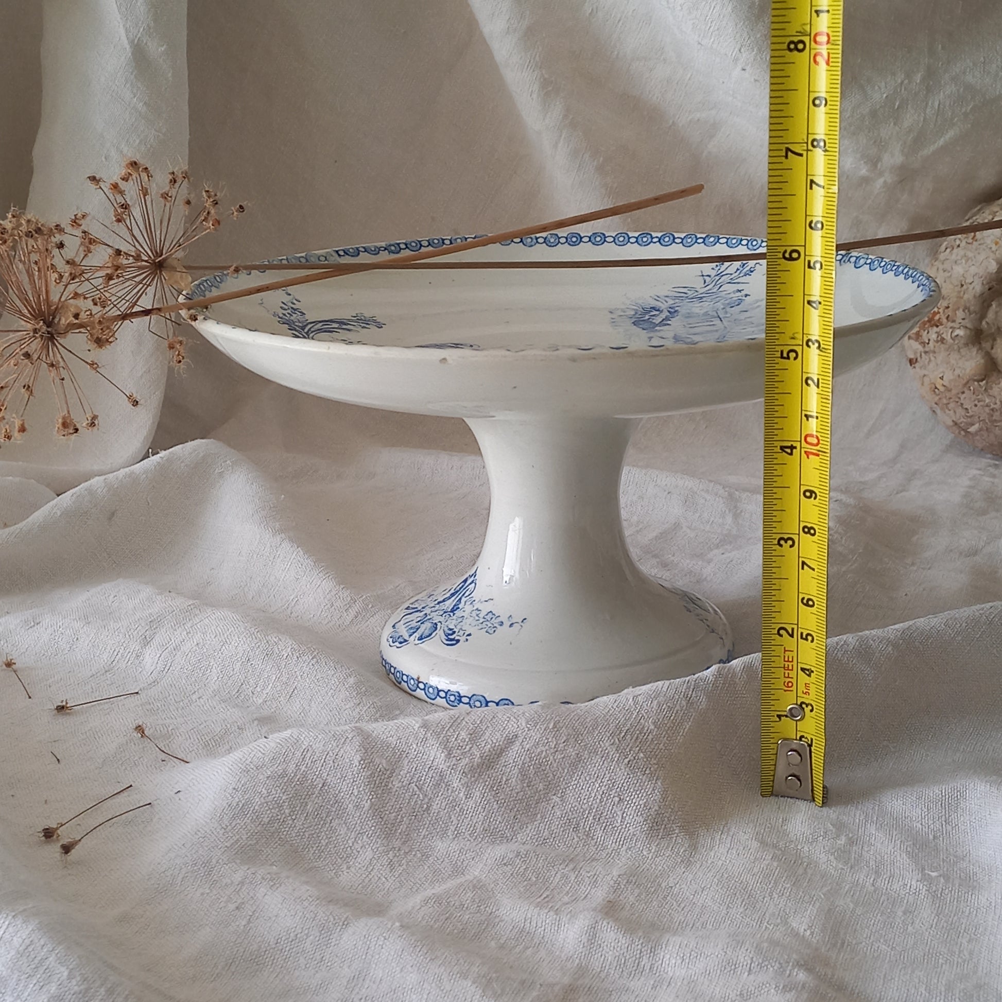 An attractive French antique footed ironstone cake plate with a blue transfer pattern depicting architecture, cherubs, and flowers; a very pretty and delicate pattern.

Original antique ironstone pieces of this age and condition are becoming increasingly difficult to source to this a rare treat to discover.
