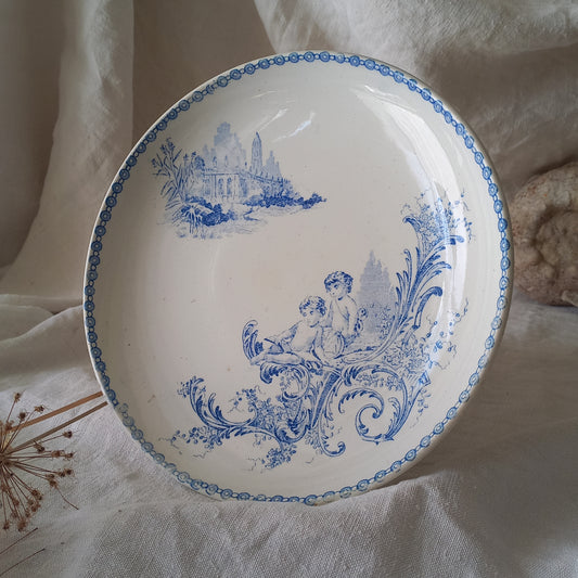 An attractive French antique footed ironstone cake plate with a blue transfer pattern depicting architecture, cherubs, and flowers; a very pretty and delicate pattern.

Original antique ironstone pieces of this age and condition are becoming increasingly difficult to source to this a rare treat to discover.
