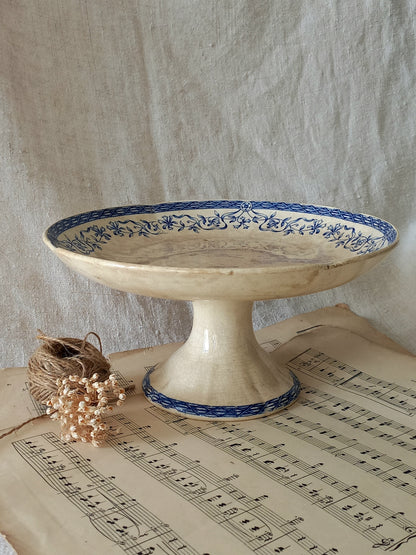 Decorative ceramic pedestal dish with blue floral patterns on a sheet of music.