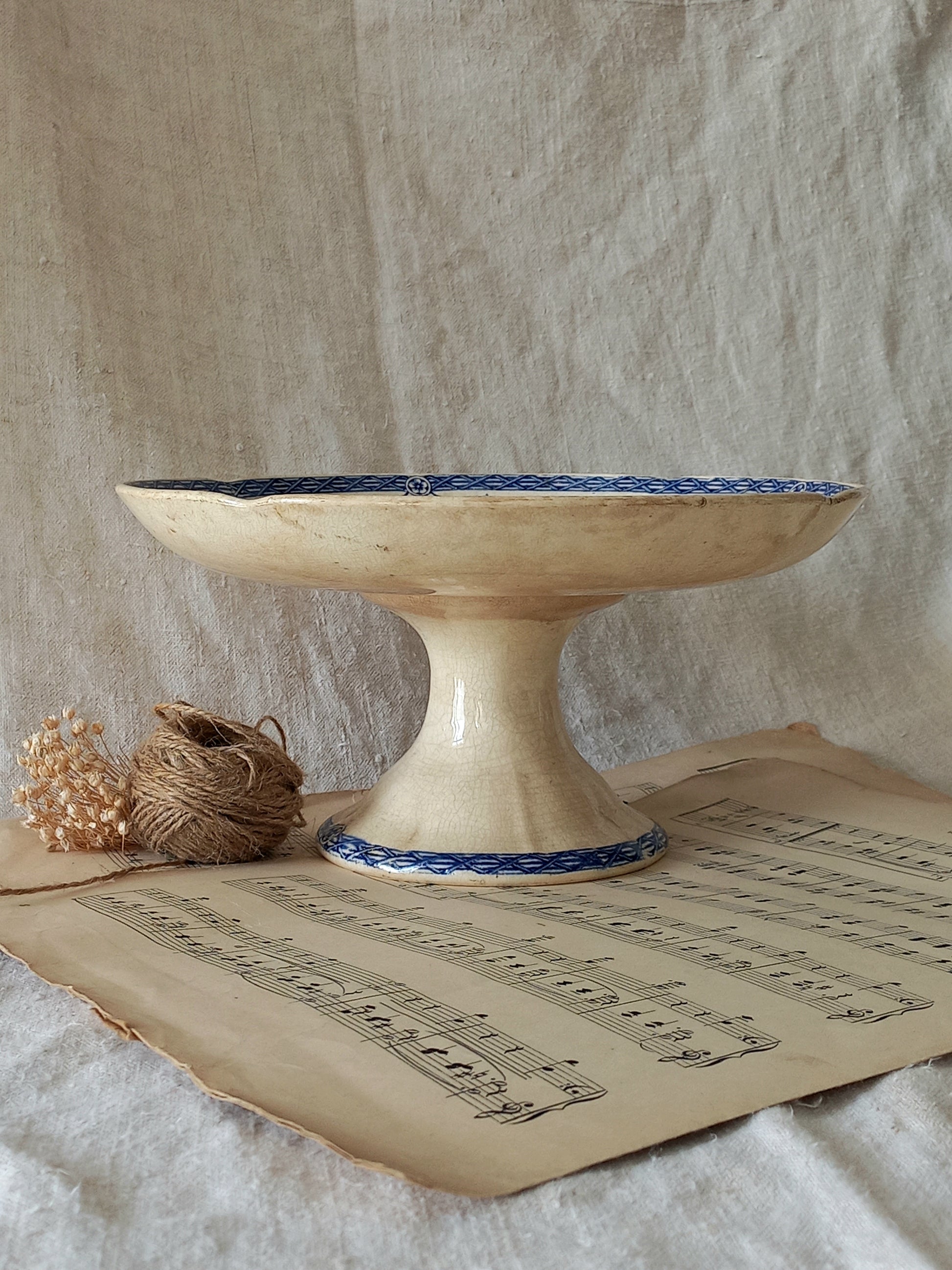 Decorative ceramic pedestal with blue decorative elements on a surface with sheet music