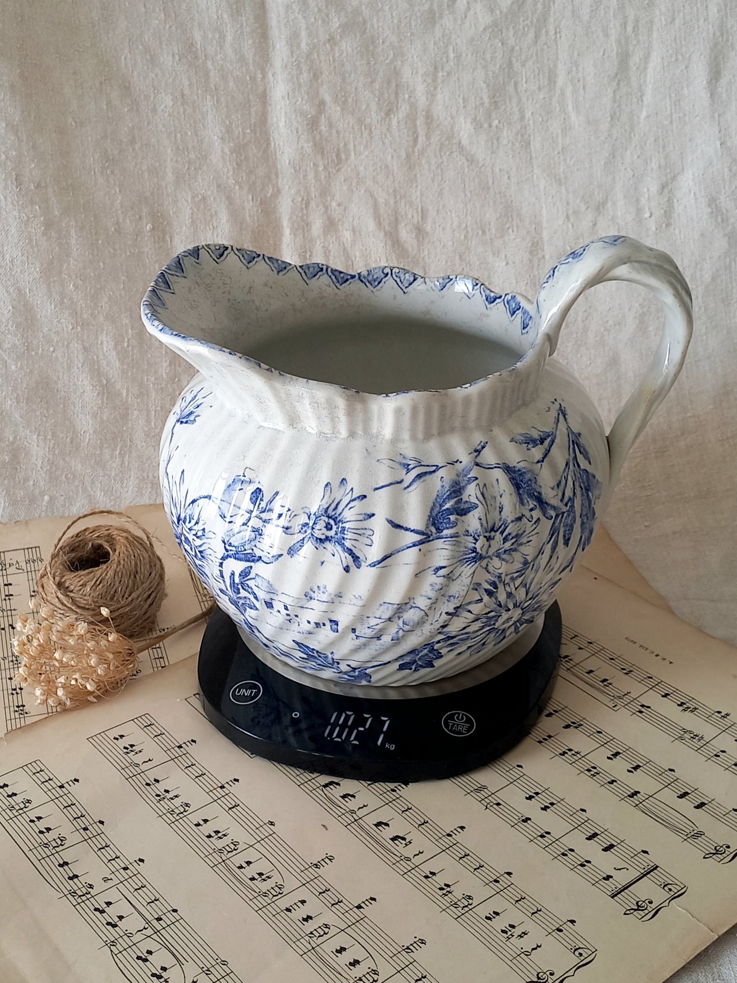 Blue and white ceramic pitcher on a digital scale with music sheet background