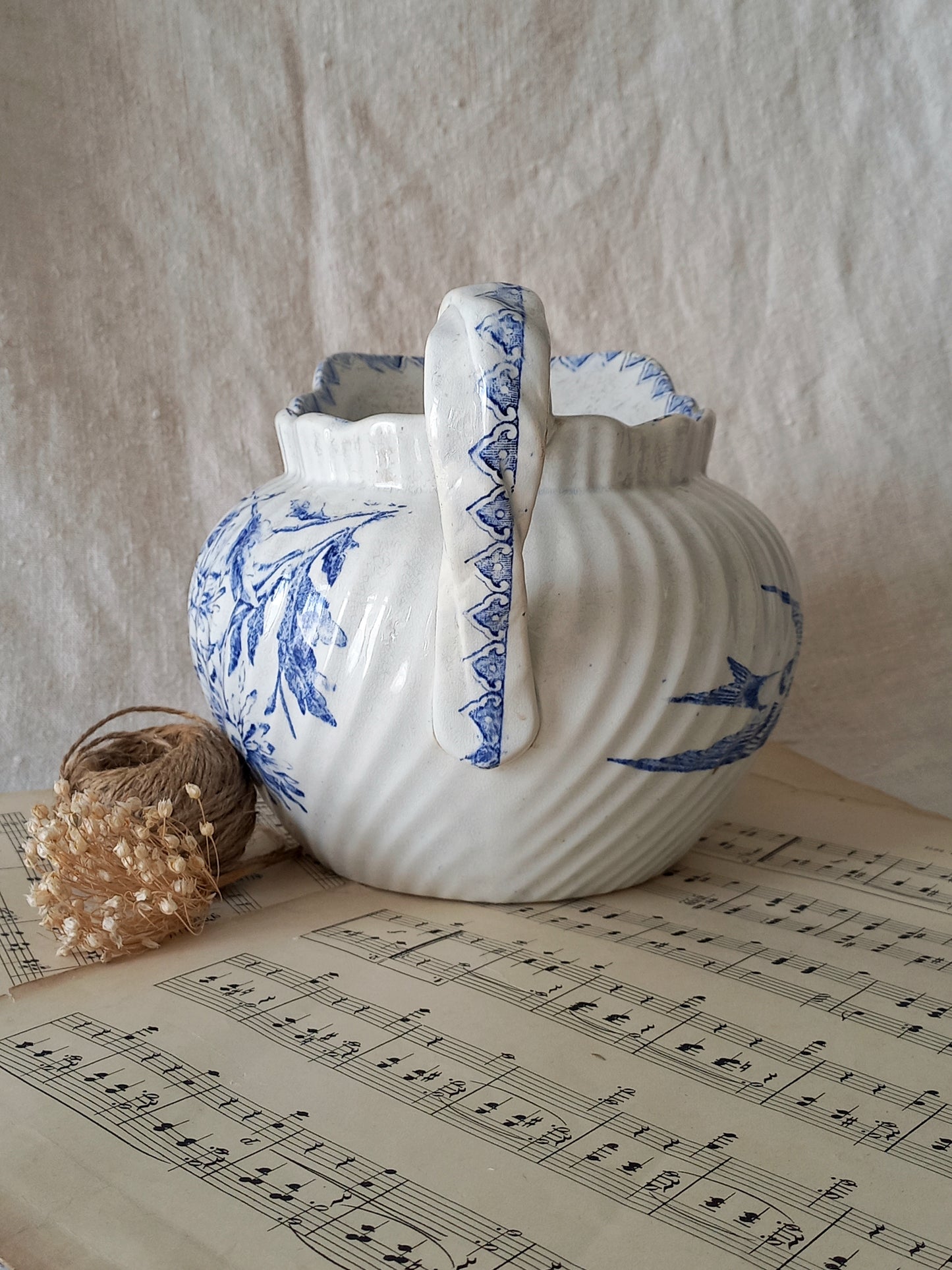 Decorative ceramic jug with blue patterns on a sheet of music