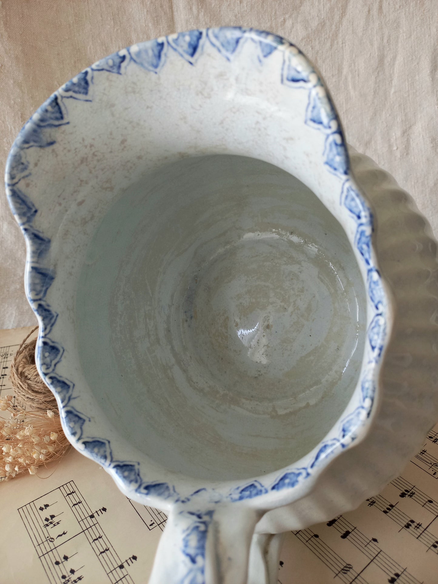Ceramic jug with blue decorative rim on a surface with music sheet background