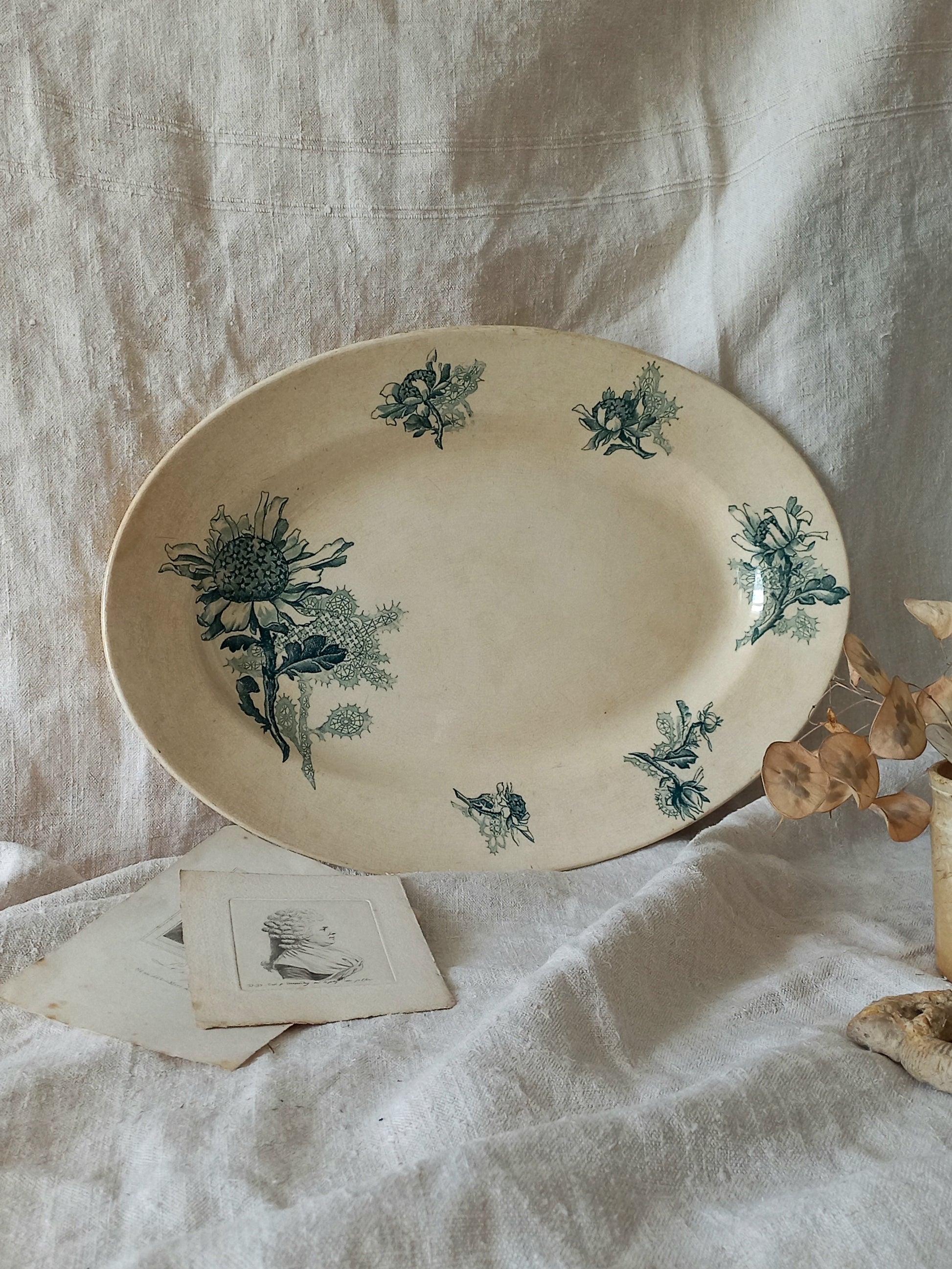 French antique oval ironstone serving plate with teal colour sunflower transferware pattern that over many decades has become a pleasing, warm shade of creamy white with crazing and tea-staining. 