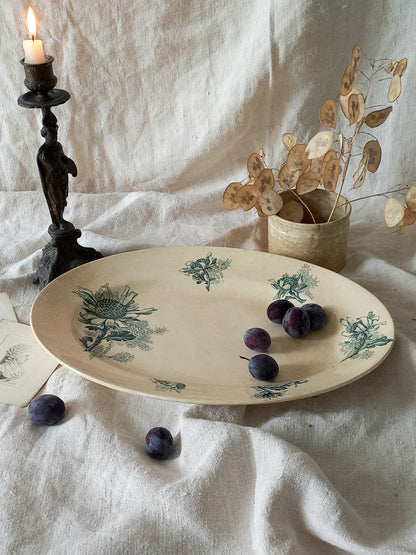French antique oval ironstone serving plate with teal colour sunflower transferware pattern that over many decades has become a pleasing, warm shade of creamy white with crazing and tea-staining. 