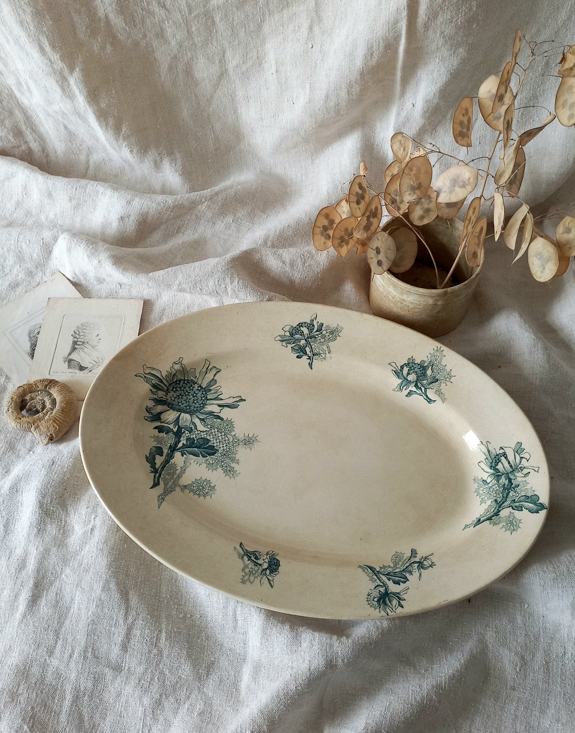 A French antique oval ironstone serving plate with teal colour sunflower transferware pattern that over many decades has become a pleasing, warm shade of creamy white with crazing and tea-staining. 